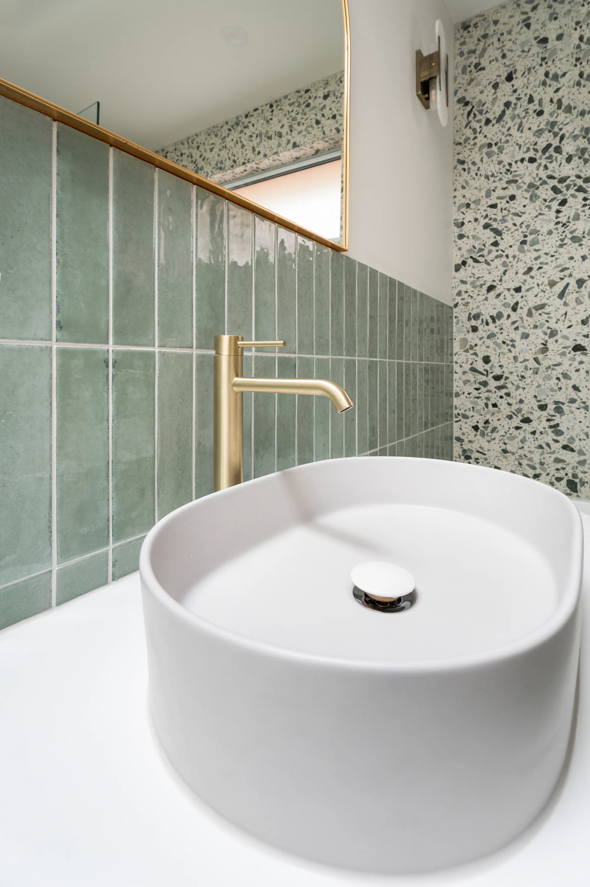 White vessel basin and wall-mounted brass tapware in the Reservoir project