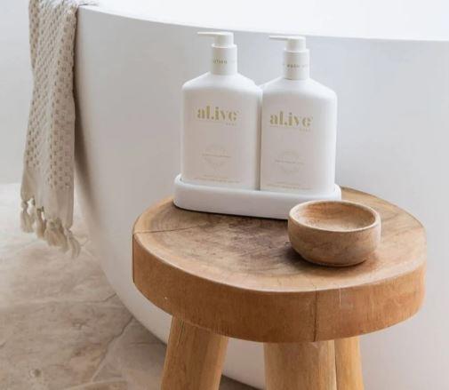 Timber stool beside a freestanding bath styled with ceramic amenities and a linen towel